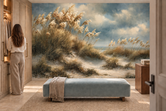 Sea oats and dune mural in a dressing room where a woman stands at a wardrobe beside a pale blue bench with a throw
